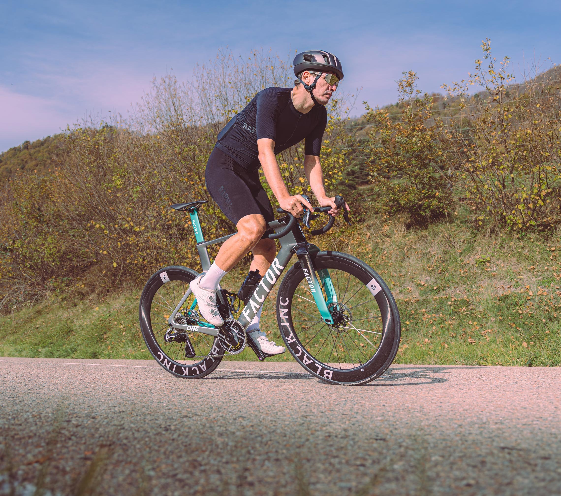 Ein Radfahrer auf dem Factor One Aero-Bike und Black Inc Laufrädern im Wiegetritt.