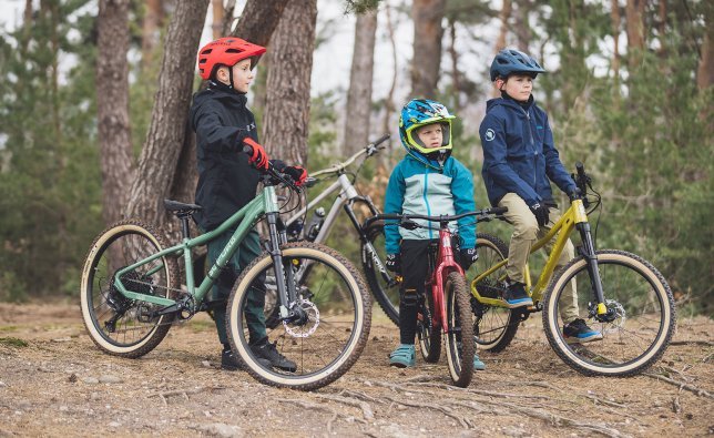 Drei Jungen mit SUPURB Mountainbikes im Wald. 