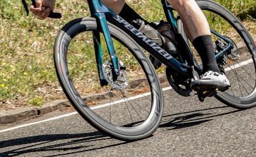 Markus aus dem bc-Service fährt auf einem Specialized Tarmac bergab durch eine Kurve. Der Fokus des Bildes liegt auf dem Vorderrad seines Bikes.