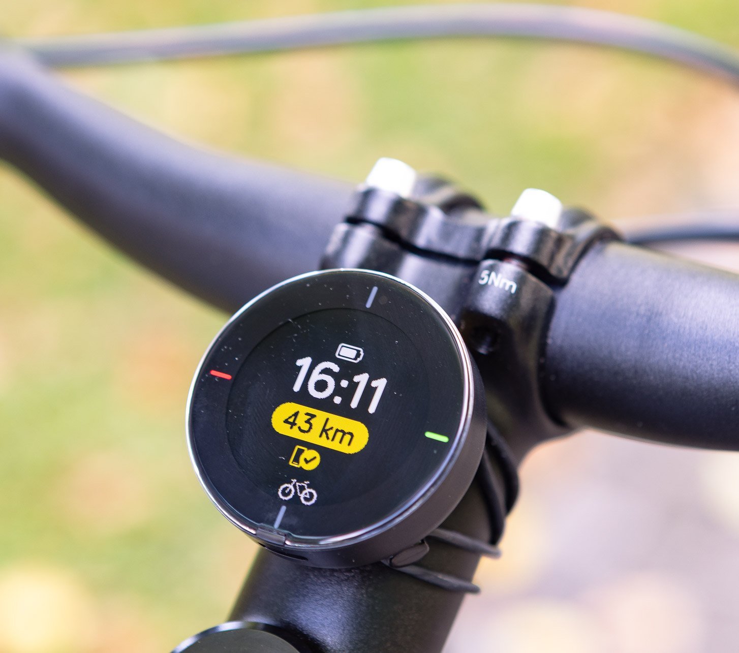 Nahaufnahme des runden Beeline-Fahrradcomputers am Lenker, der Uhrzeit, Akkustand und verbleibende Strecke anzeigt – intuitives Navigationsgerät für moderne Bike-Touren.