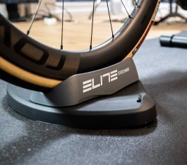 Foto de detalle: La rueda delantera de una bicicleta de ruta está colocada sobre un soporte delantero “Elite Sterzo Smart”.