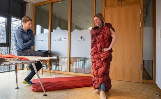 Svenja wears the sleeping bag from the Meglis series as an enormous coat. This is amusing both for her and for Markus from VAUDE.