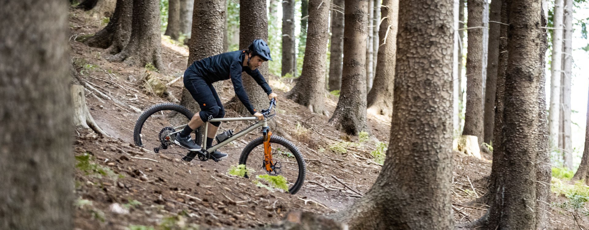 Un ciclista de montaña monta por un sendero en el bosque en una bc original Podsol.