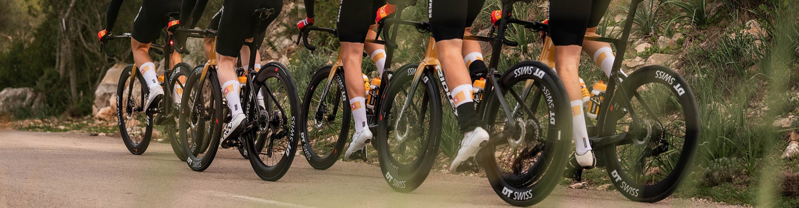 Rennradfahrer im Teamtraining auf kurviger Bergstraße mit DT Swiss ARC 1100 DICUT 50 Carbon-Laufrädern für Aero-Performance und maximale Geschwindigkeit