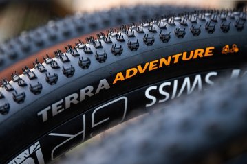 Detailaufnahme des Continental Terra Adventure Gravelreifens mit markantem Stollenprofil und Schriftzug, ideal für Offroad-Abenteuer und maximale Traktion. 