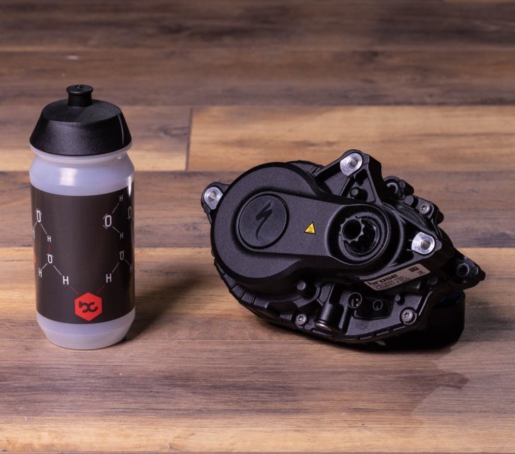 A Specialized 3.1 e-bike drive on a dark wooden floor. Next to it is a bike water bottle