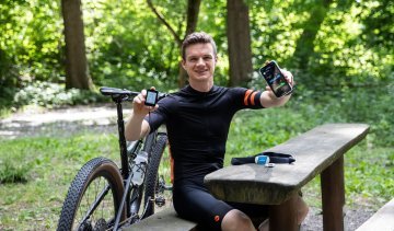 Christof, de gestión de productos de bc, sosteniendo frente a la cámara un ciclocomputador Garmin Edge y su smartphone, que muestra sus datos de rendimiento.