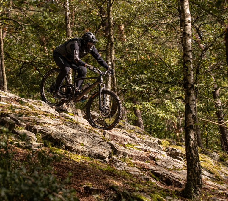 Ein Biker auf einem MTB fährt über einen Felsen