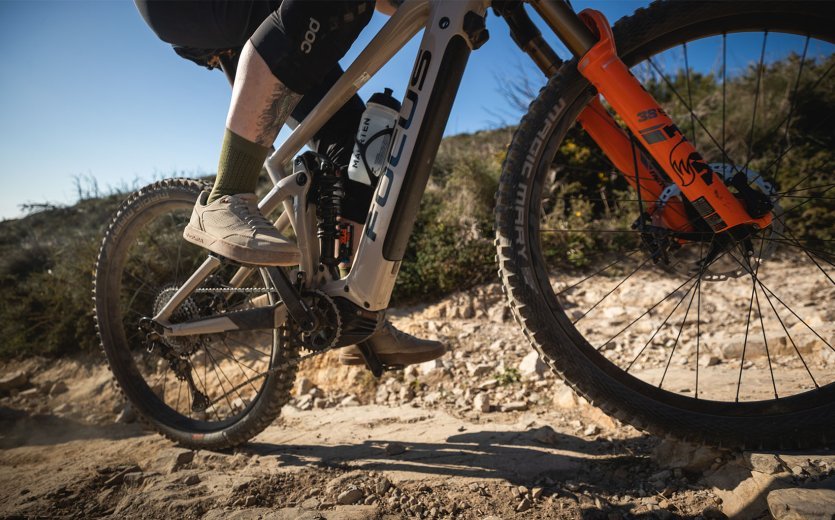 Isa from the bc Service department rides a Focus full-suspension over sandy ground.