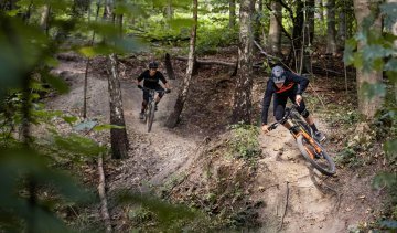 Christoph and Georg from bc ride their bc original Podsol bikes over a trail in the forest.