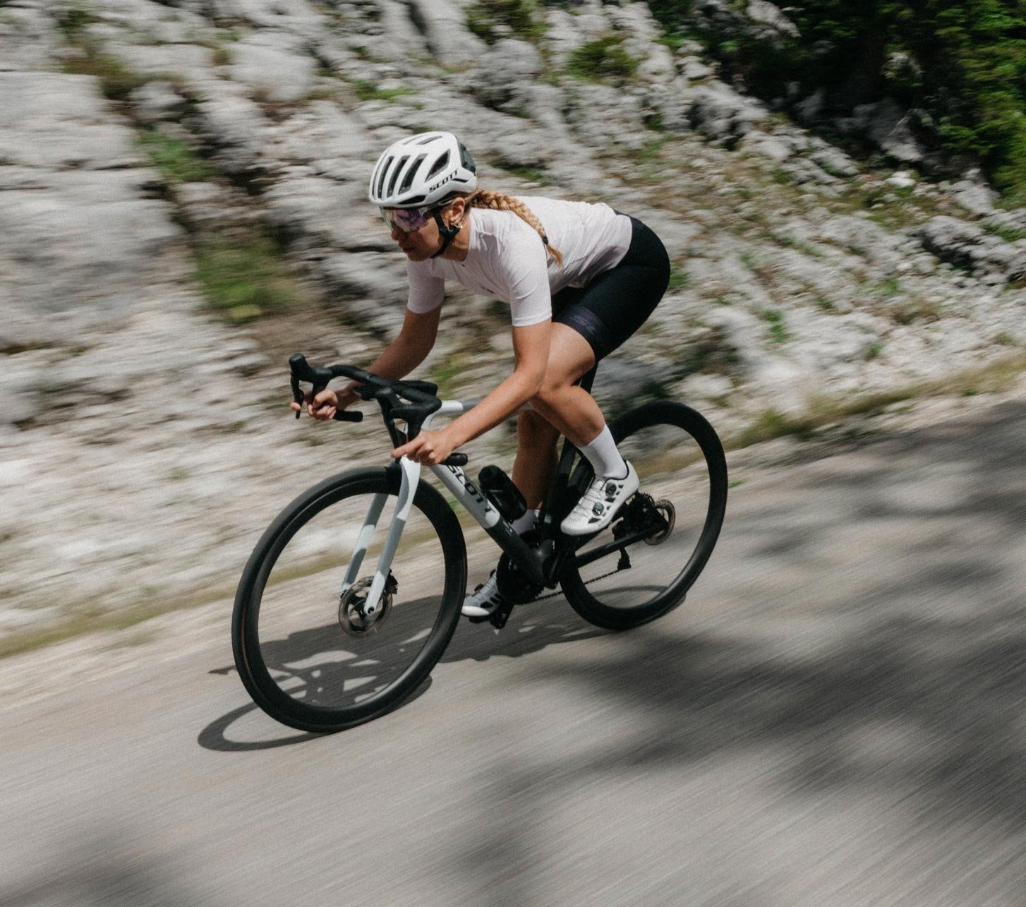 Ciclista de carretera con ropa de ciclismo Scott sobre una bicicleta de carretera Scott en una carretera de montaña