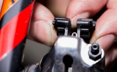 Gros plan d’une main retirant les plaquettes d’un étrier de frein hydraulique de vélo.