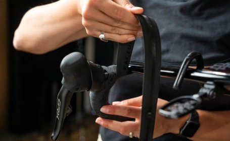 Die Mechanikerin führt das Lenkerband unterhalb des Oberlenkers nach innen und nach oben.