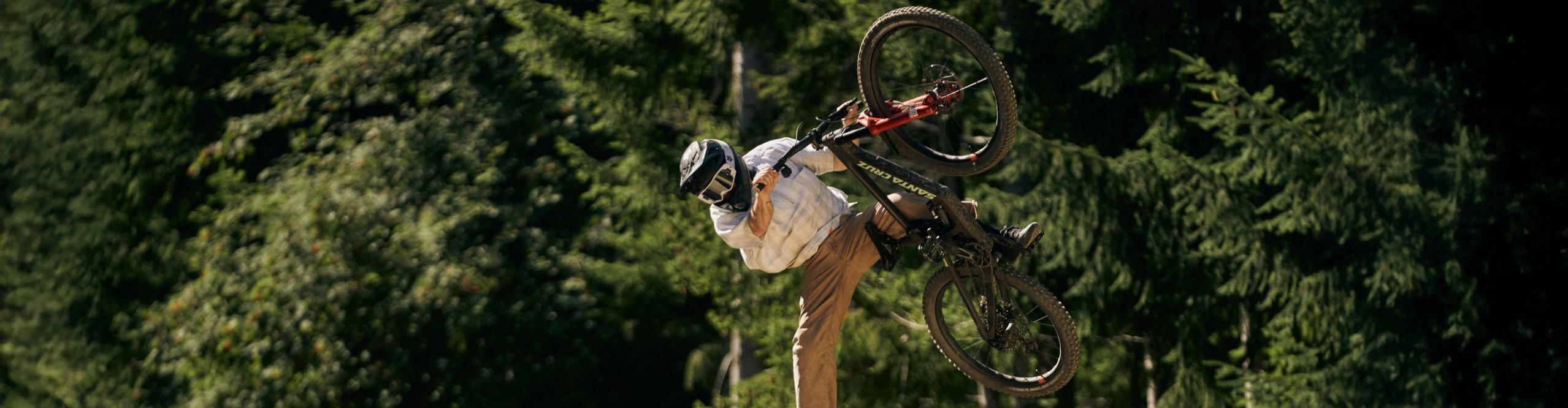 Vététiste en saut avec un Santa Cruz Nomad sur un trail de bike park en forêt.