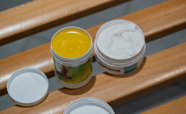 Se muestran abiertas las latas de crema chamois de Eule y la crema chamois de Assos. 