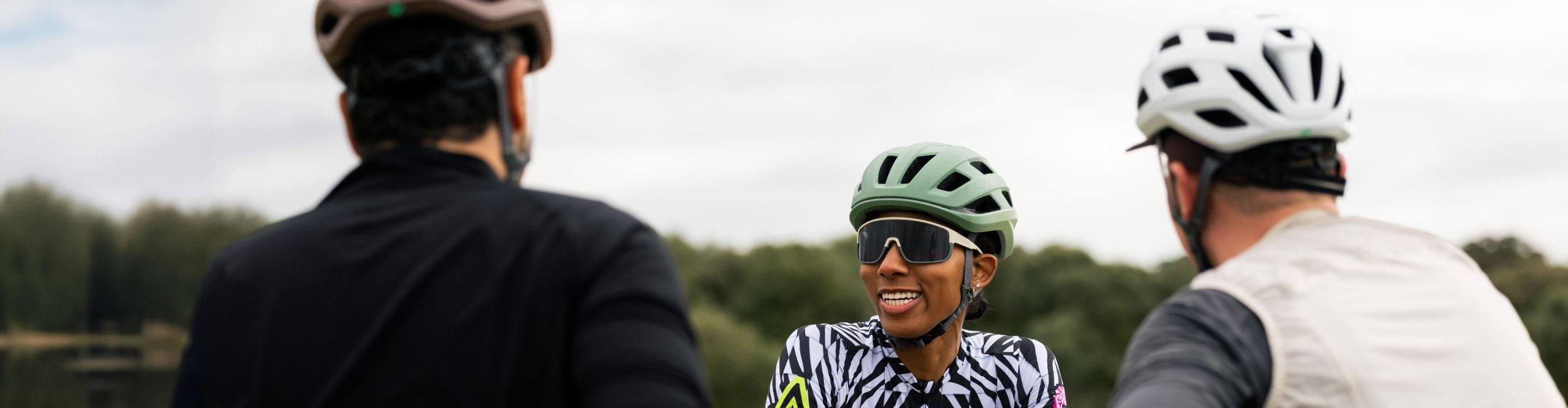 Three road cyclists wearing Lazer Blade KC helmets during a group ride break in the countryside.