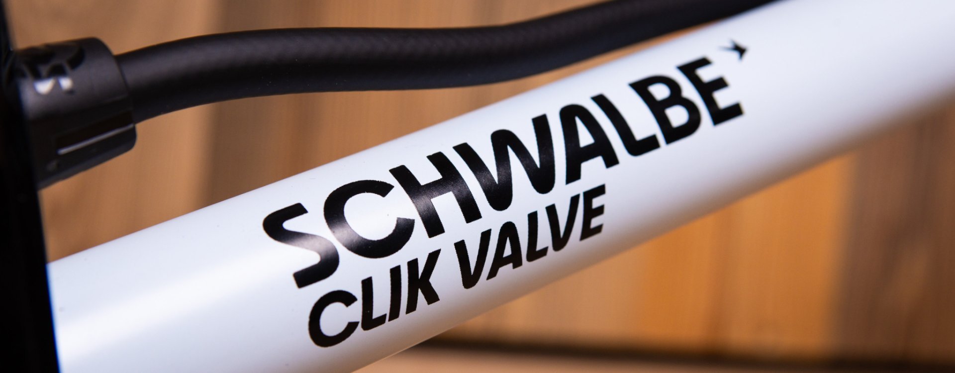 Close-up: The white cylinder of an SKS floor pump for the Schwalbe Clik Valve with black lettering.