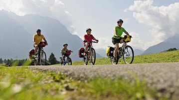 Eine Familie unterwegs auf einer Radtour in den Bergen mit Gepäck
