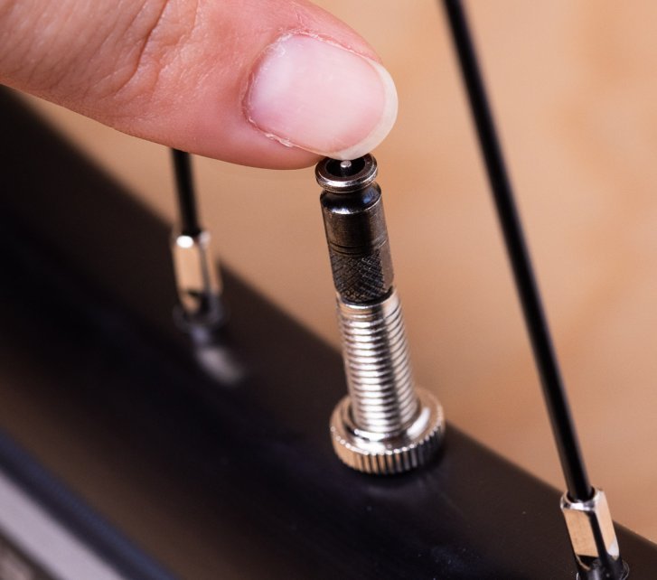 The edge of a fingernail is used to press down the pin inside a Clik Valve to release air.