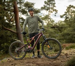 Berno steht im Wald hinter seinem lilafarbenen Specialized Turbo Levo 3 LTD. mit Öhlins-Fahrwerk. 