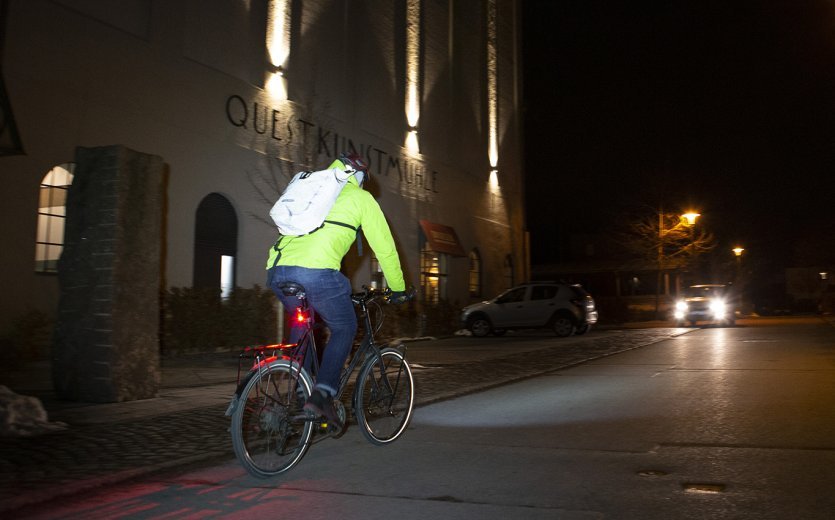Radfahrer im Straßenverkehr, nachts. Reflektierender Rucksack.