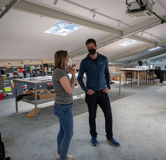 bc-Brandmanagerin Svenja und Vaude-Produktmanager Markus im Gespräch auf einer lichtdurchfluteten Galerie.