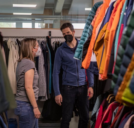 bc-Brandmanagerin Svenja und Vaude-Produktmanager Markus stehen stehen vor einem Schrank mit bunten Jacken.