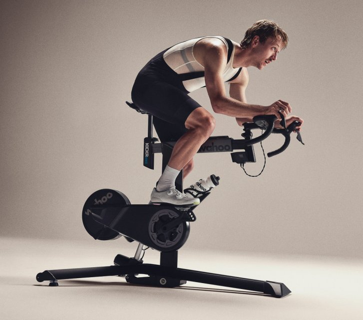 A man trains on a Wahoo smart bike in the white, seamless backdrop of a photo studio.