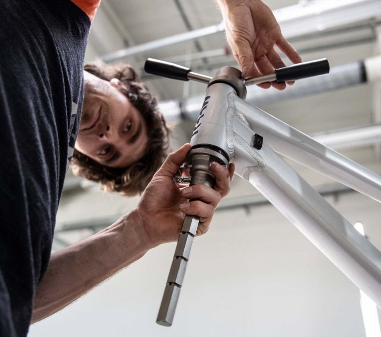 A mechanic presses the bearing cups of his Zero Stack headset into a RAAW Madonna frame.