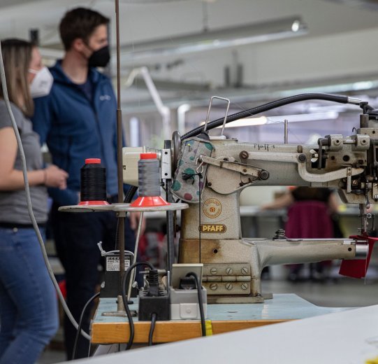 bc-Brandmanagerin Svenja und Vaude-Produktmanager Markus vor einer Nähmaschine.