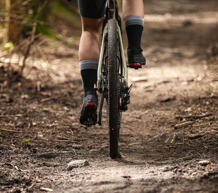 La photo montre la roue arrière d'un vélo de gravel bc original Flint. Le cadrage montre le vélo de derrière, de sorte que toute la largeur du pneu est visible.