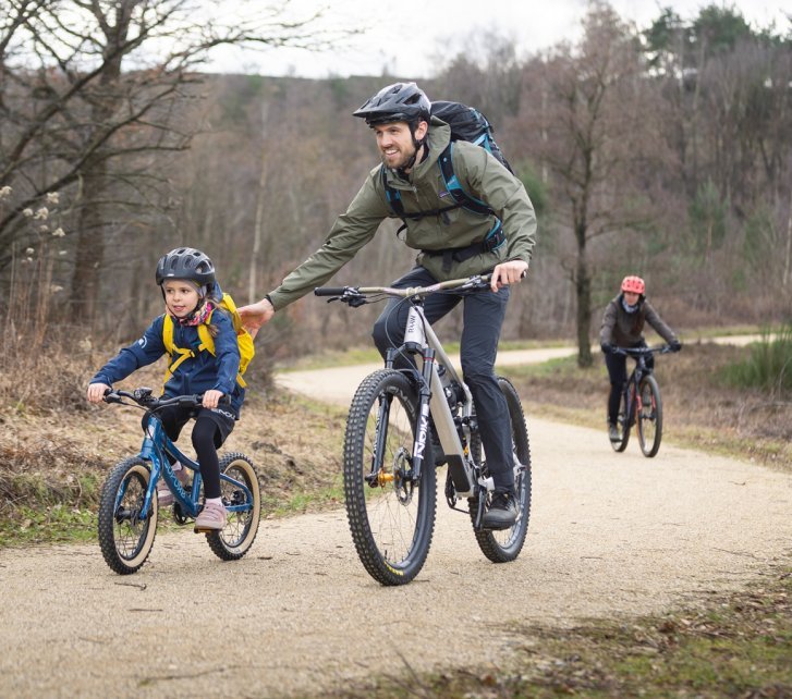 Un enfant et un adulte font du cyclisme tout-terrain. Ils sont en route sur un chemin de gravier.