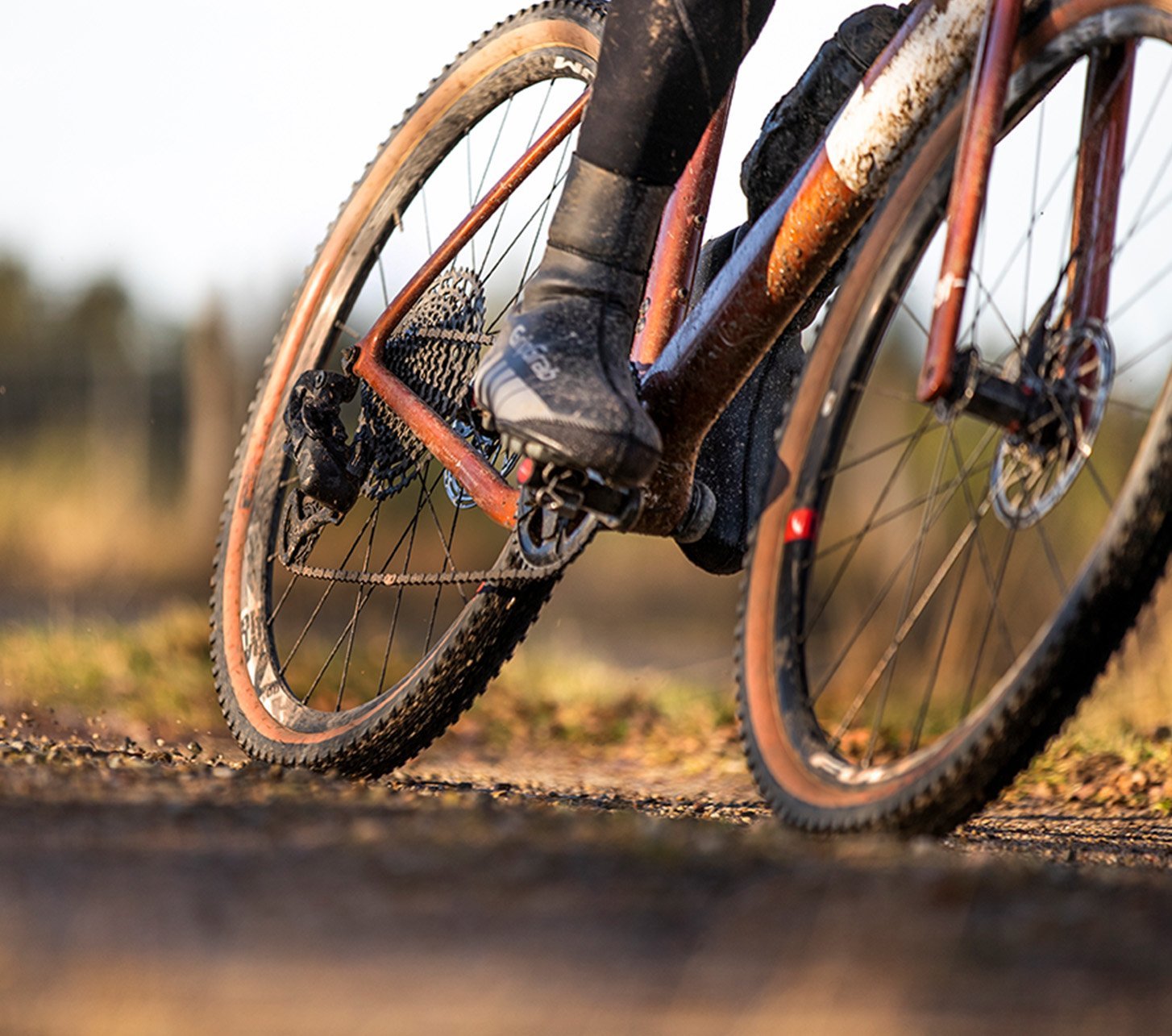 Gravelbiker fährt auf Forstweg in Schräglage durch eine Kurve.