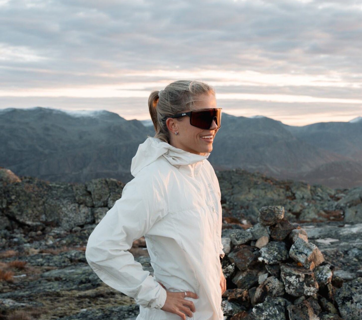 Sportlerin auf Gipfel vor Bergpanorama mit bliz Sportbrille bei Sonnenaufgang
