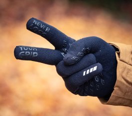 Eine rechte Hand in einem schwarzen Strickhandschuh formt ein Victory-Zeichen. Auf den Innenseiten von Zeige- und Mittelfinger kann man "Never lose your Grip" lesen.