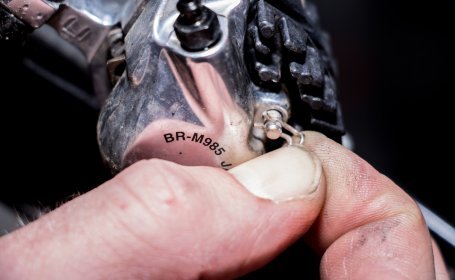 Gros plan d’un doigt retirant la goupille de maintien d’un étrier de frein Shimano BR-M985 afin d’enlever les plaquettes.