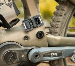 Blick auf die geöffnete Ladebuchse eines bronzegrünen Turbo Levo 4 über dem Motor/Tretlagerbereich 