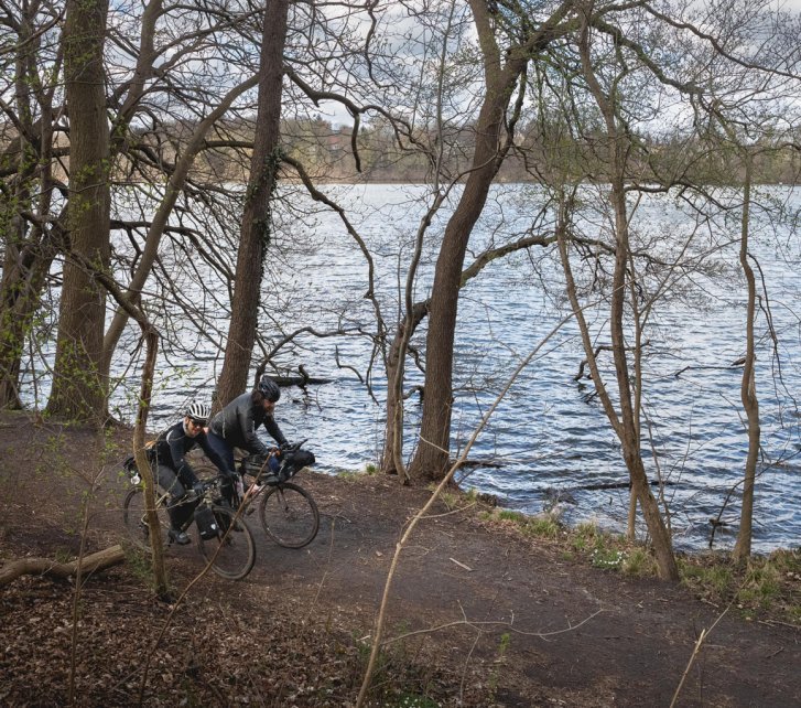 Christian und Marcel radeln über einen Uferweg entlang der Elbe.