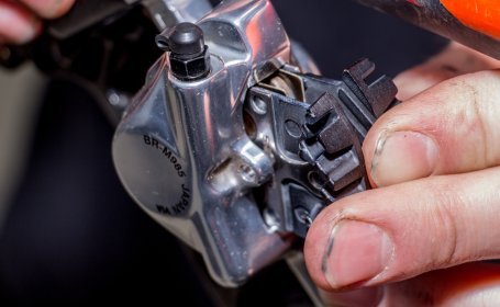 Gros plan d’une main insérant de nouvelles plaquettes de frein Shimano dans un étrier BR-M985.