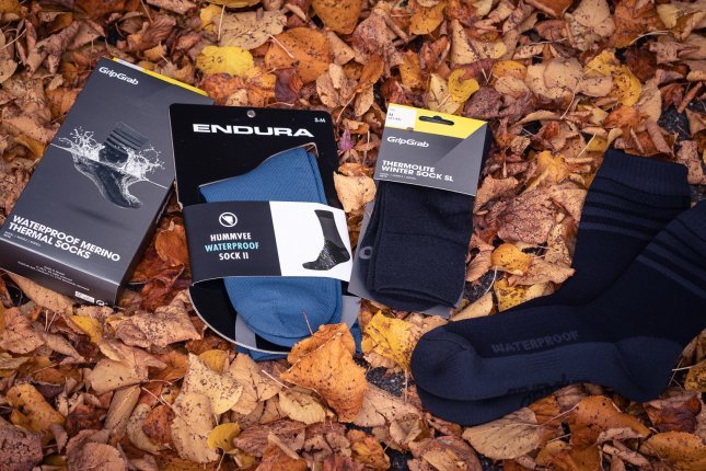 Cuatro pares de calcetines de invierno sobre hojas otoñales rojizas.