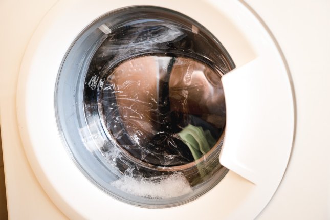 Eine Ladung Funktionswäsche in einer Waschmaschine. Durch den Glasdeckel der Klappe kann man in die Trommel sehen.
