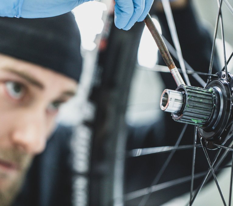 A mechanic is greasing a wheel freehub.