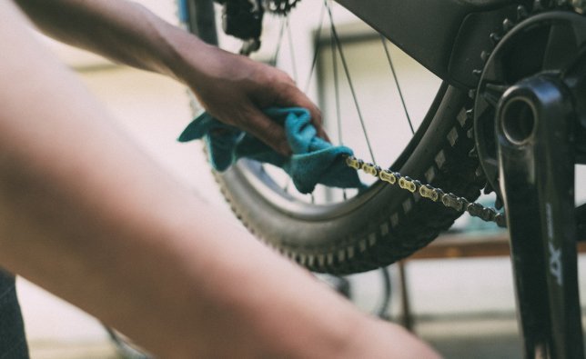 Quelqu'un essuie la chaîne d'un vélo avec un chiffon. 