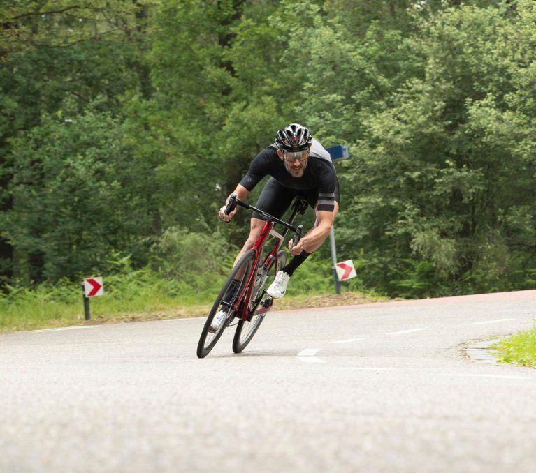 Ein Rennradfahrer in bc original Jersey und Bib fährt auf einem Factor One eine Abfahrt hinab.