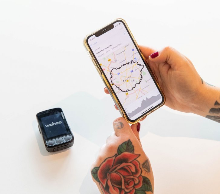 Eine auf Komoot geplante Route wird von einem Smartphone auf einen Wahoo ELEMNT Bolt 2.0 übertragen.