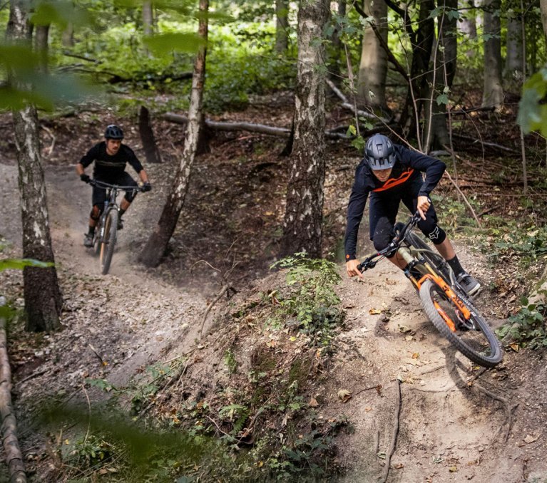 Christoph und Georg von bc fahren auf ihren bc original Podsol Bikes über einen Trail im Wald.