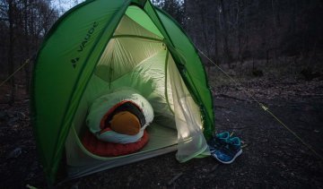 Svenja aus dem bc Produkt Management liegt warm eingepackt in ihrem Deuter Schlafsack in einem VAUDE Zelt.