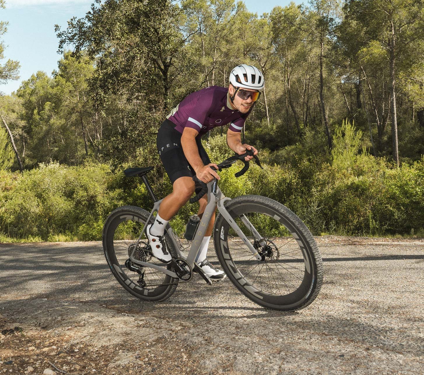 Gravel cyclist rides an OPEN WI.DE with Zipp wheels on a gravel road through the forest.