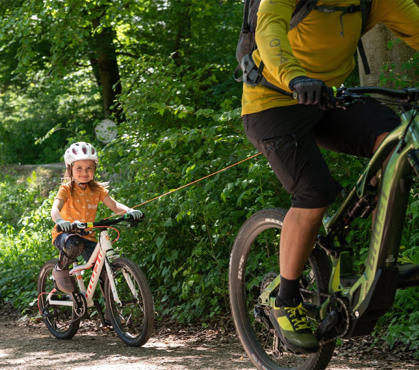 Kind wird mit dem kommit Bike-Zugsystem vom Papa hinter dem Fahrrad gezogen.