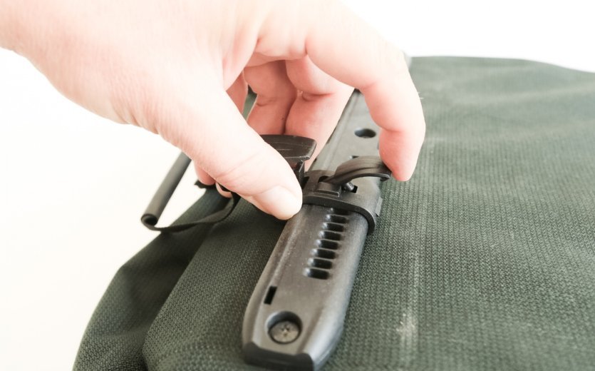 Eine Hand, die die Verriegelung der Ortlieb Back Roller Urban Tasche mit dem Finger hochklappt und die Position einstellt.